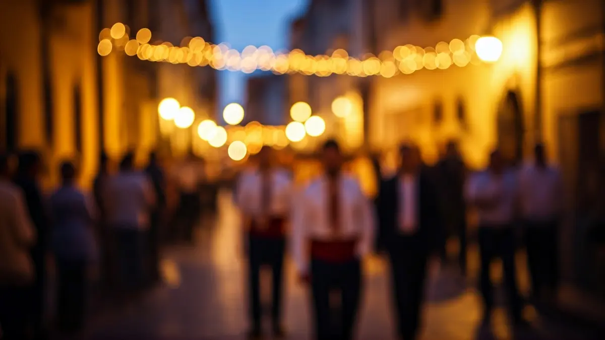 Imagen de una procesión de Semana Santa en un pueblo andaluz, con luces y gente borrosa.