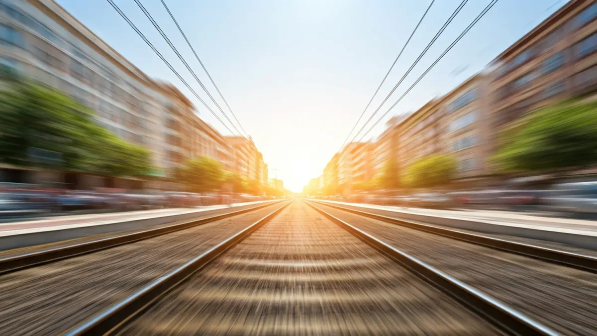 Imagen genérica de una vía de tren en un entorno urbano bajo un cielo azul.