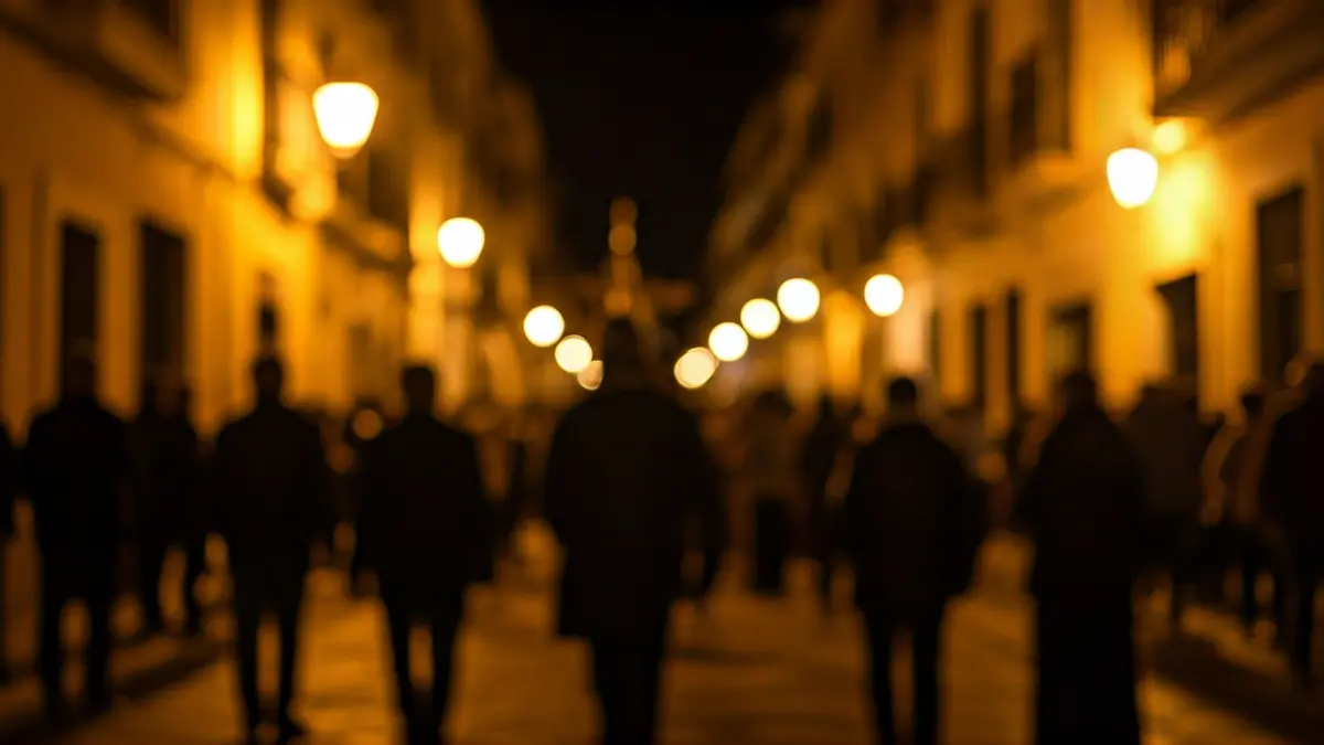 Image of a street in Cádiz during Holy Week, with lights and silhouettes of people.