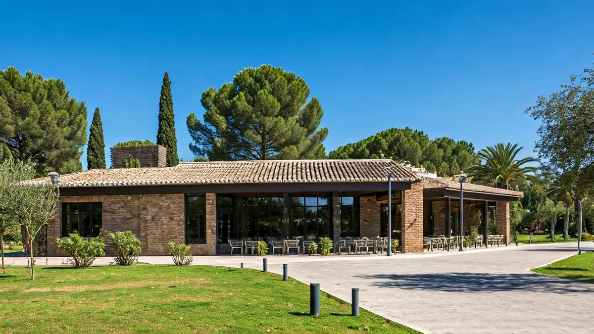 Imagen de un restaurante moderno en un parque natural, con vegetación y cielo azul.