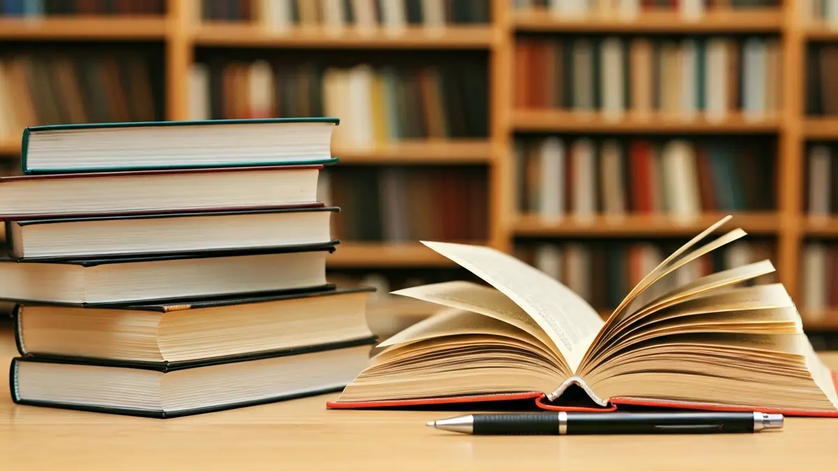 Generic image of books and a pen on a table in a library.