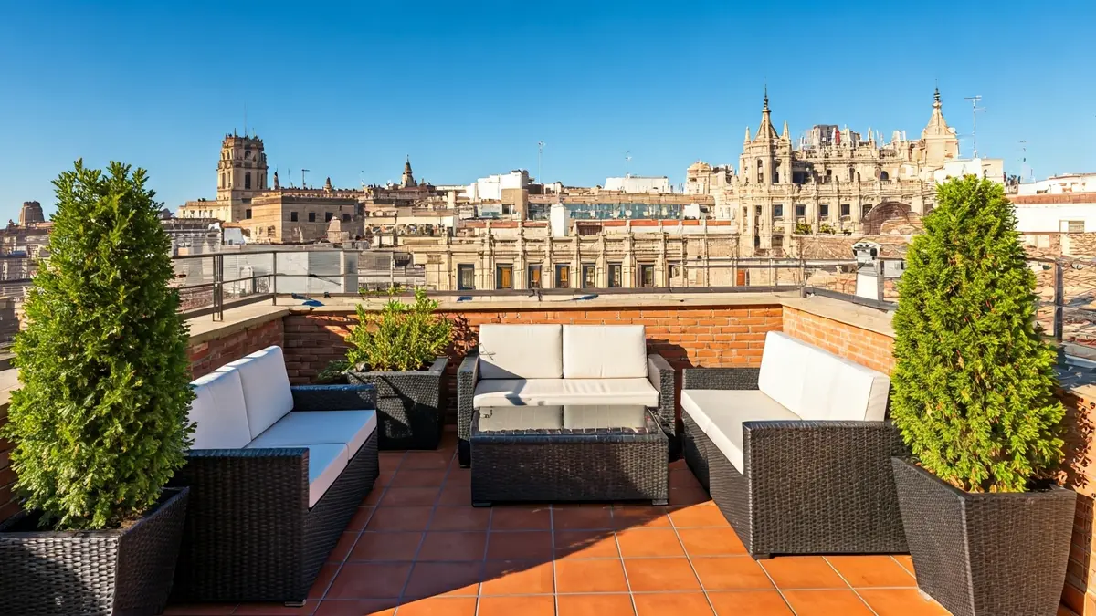 Rooftop terrace of a building in Spain, with plants and outdoor furniture.