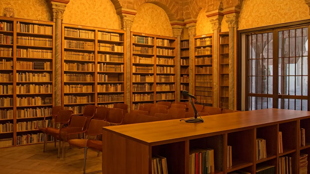 Imagen genérica de una sala de presentación literaria con un micrófono y sillas vacías.