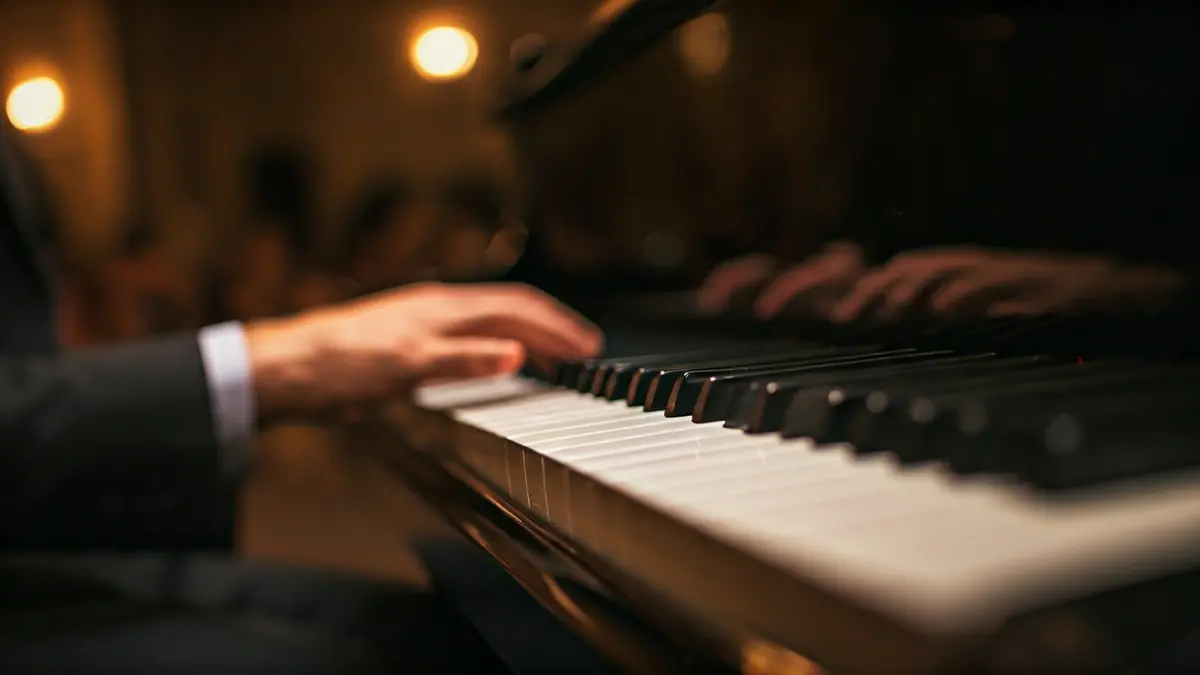 Generic image of a piano keyboard with hands playing, soft stage lighting.