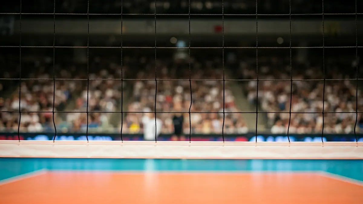 Generic image of a volleyball net with a blurred court and audience in the background.