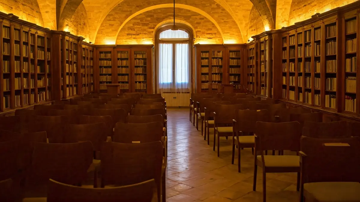 Imagen genérica de un interior de biblioteca o sala de conferencias con un podio y sillas, iluminado cálidamente.
