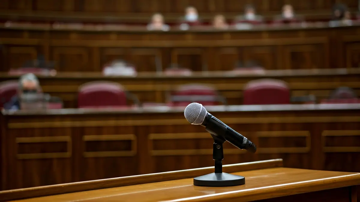 Imagen genérica de un micrófono en un atril en un salón de actos, simbolizando un debate político.
