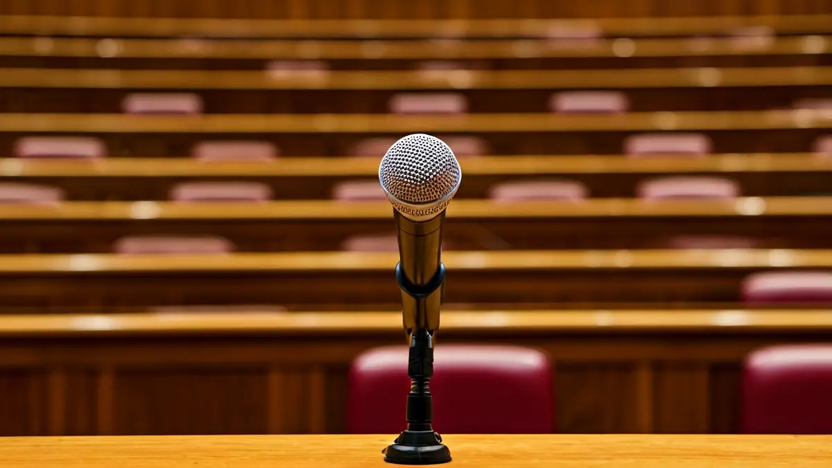 Imagen genérica de un micrófono en un atril en un salón de actos, simbolizando un evento político.