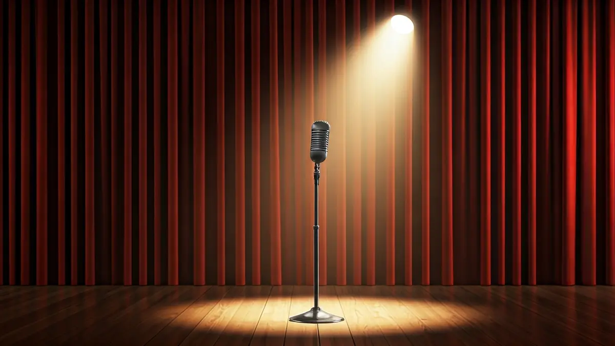 Imagen genérica de un escenario teatral con un micrófono, cortinas rojas y luz dramática.