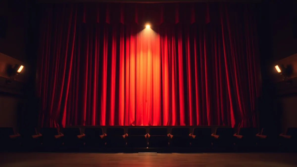 Imagen genérica de un escenario de teatro con cortinas rojas y un foco de luz.