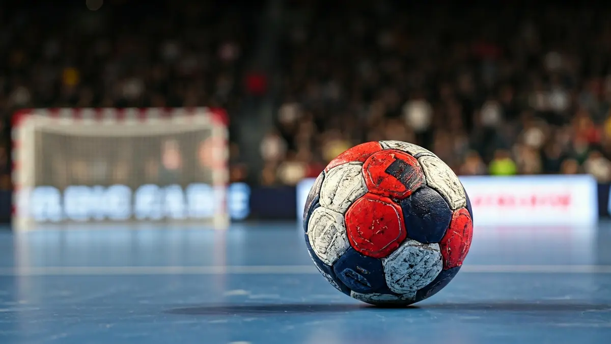 Imagen genérica de un balón de balonmano en la cancha, con la portería desenfocada al fondo.