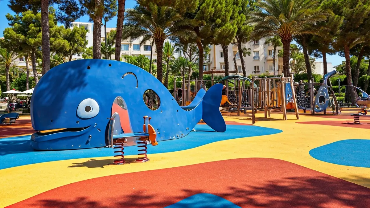 Image of an inclusive children's playground with a whale structure and other games, on a colorful rubber surface.