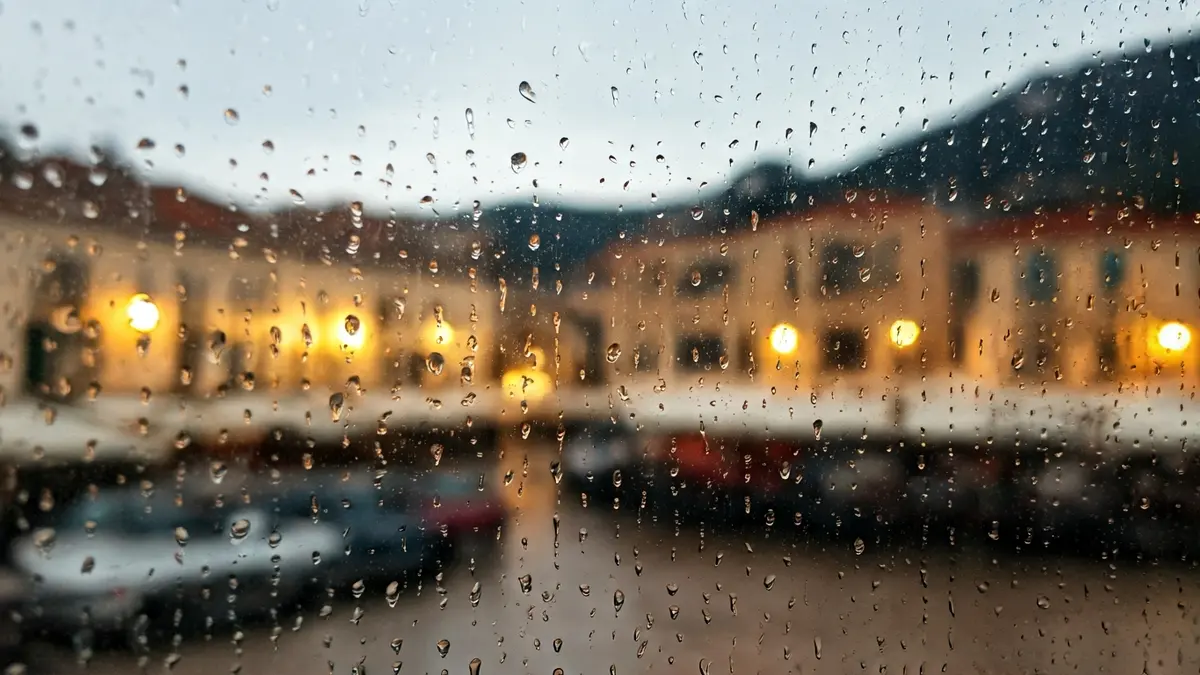 Imagen genérica de gotas de lluvia en un cristal, con luces urbanas borrosas al fondo.