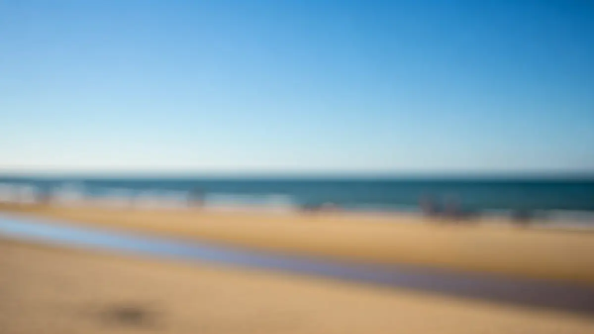 Imagen genérica de una playa soleada en Huelva con bañistas difuminados.