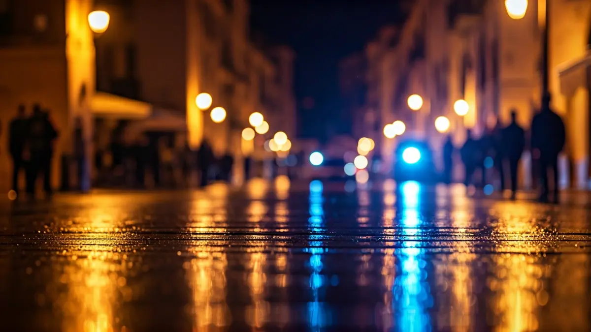 Imagen genérica de luces de emergencia reflejadas en una calle mojada al anochecer.