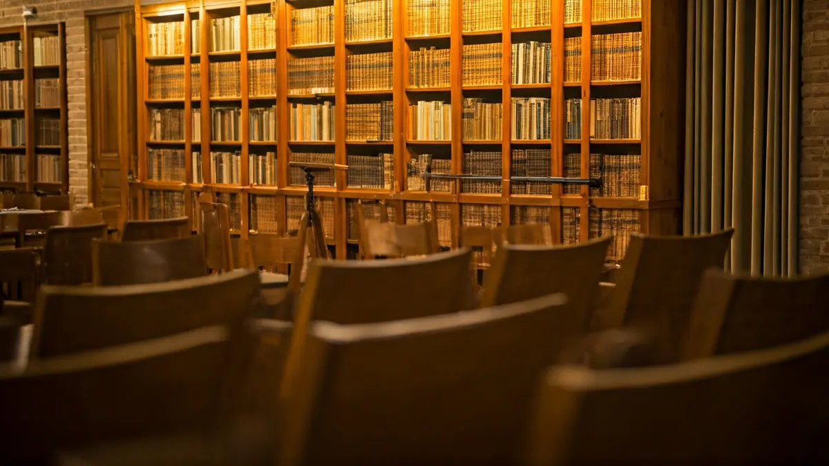 Generic image of a library with a podium and chairs, warmly lit.
