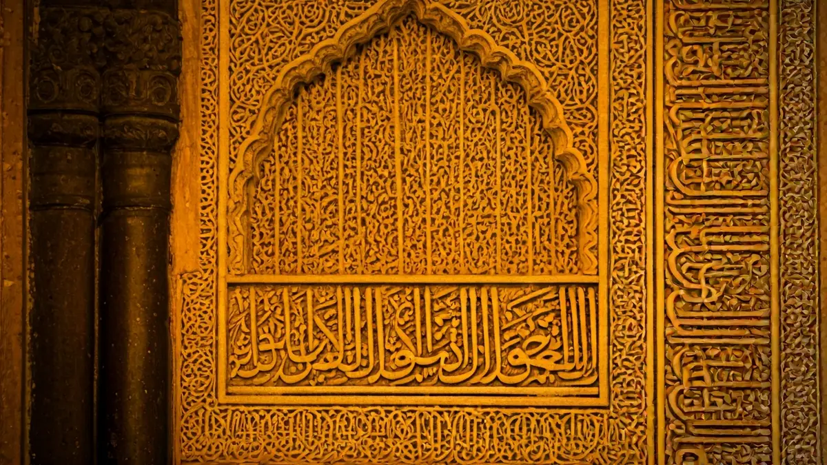 Detalle de los intrincados patrones geométricos y caligrafía árabe en la Alhambra de Granada.