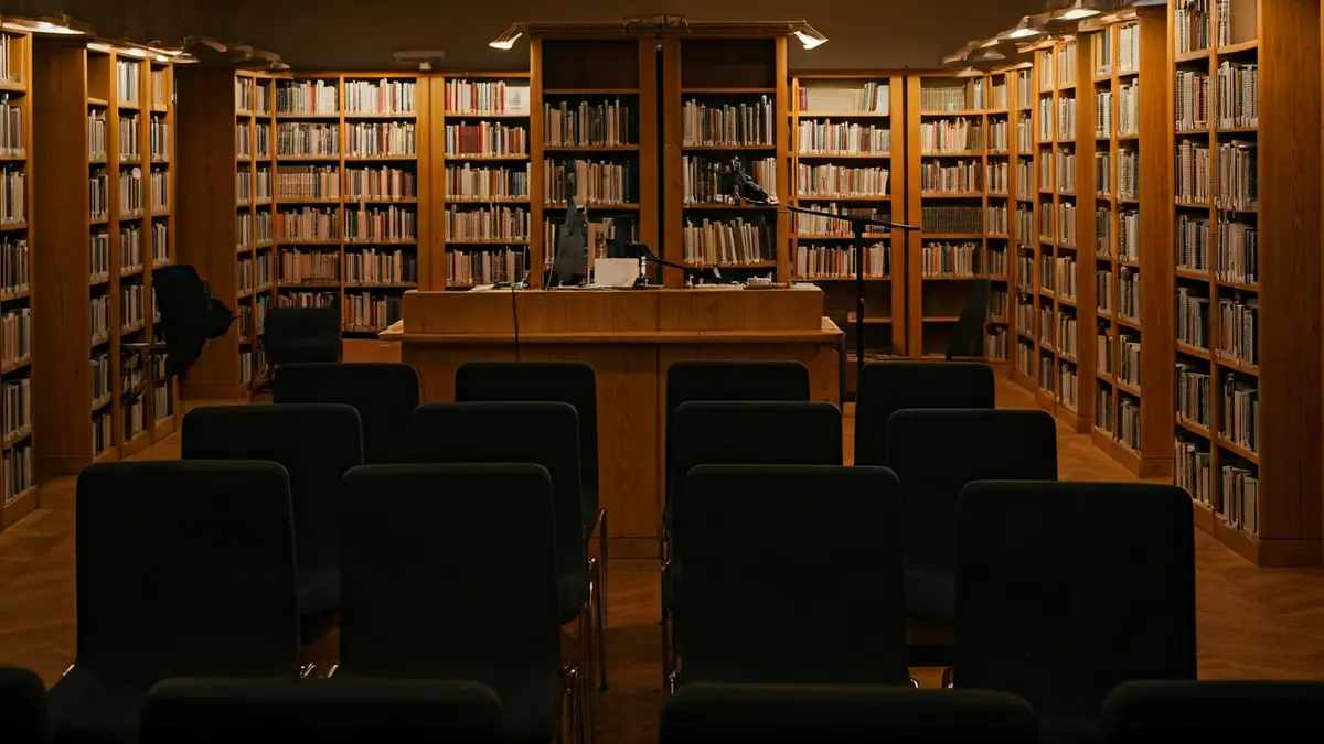 Imagen genérica de una biblioteca con un podio y sillas, iluminada cálidamente.