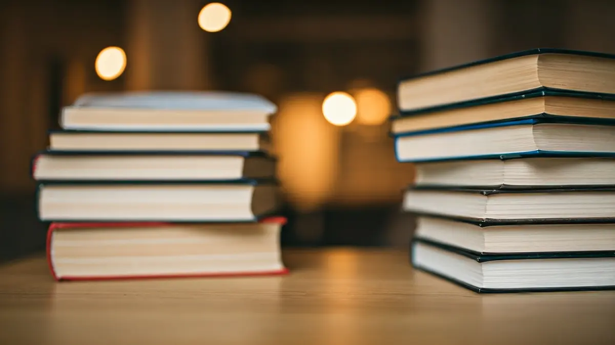 Imagen genérica de una pila de libros sobre una mesa de madera, con luz cálida, evocando un ambiente de lectura.