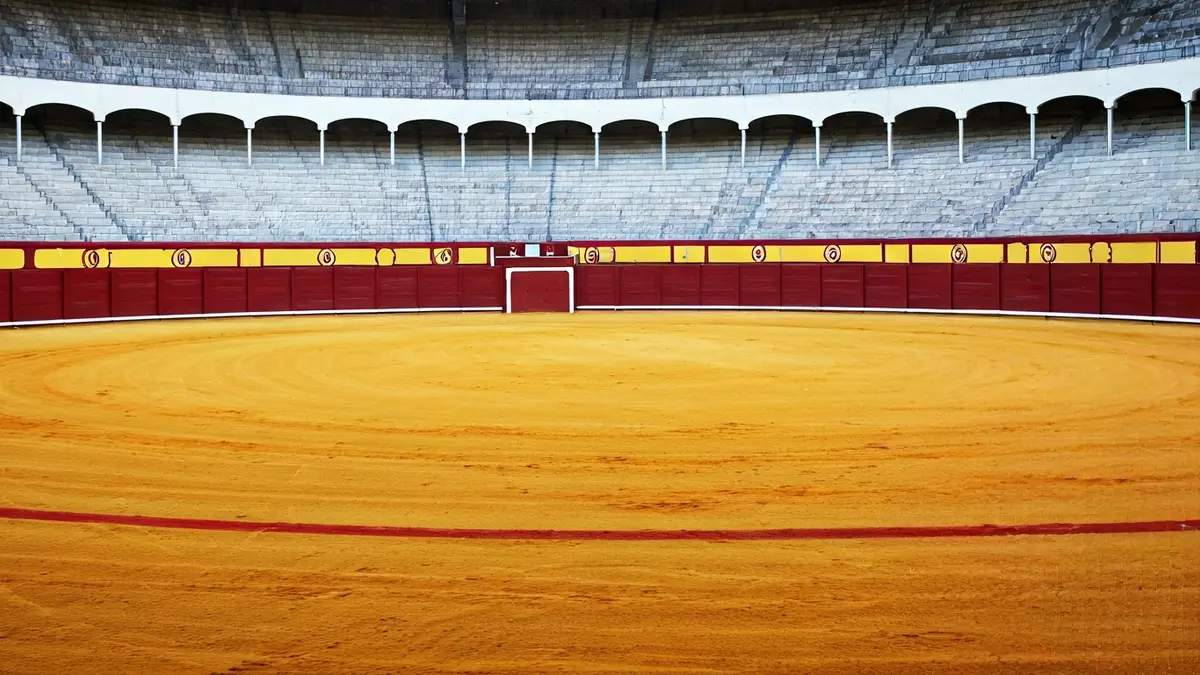 Generic image of an empty bullring under the sun.