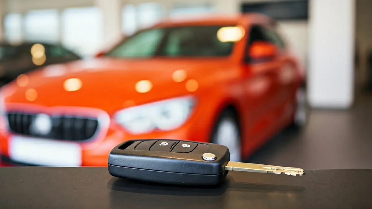 Imagen genérica de una llave de coche con un coche nuevo desenfocado al fondo.