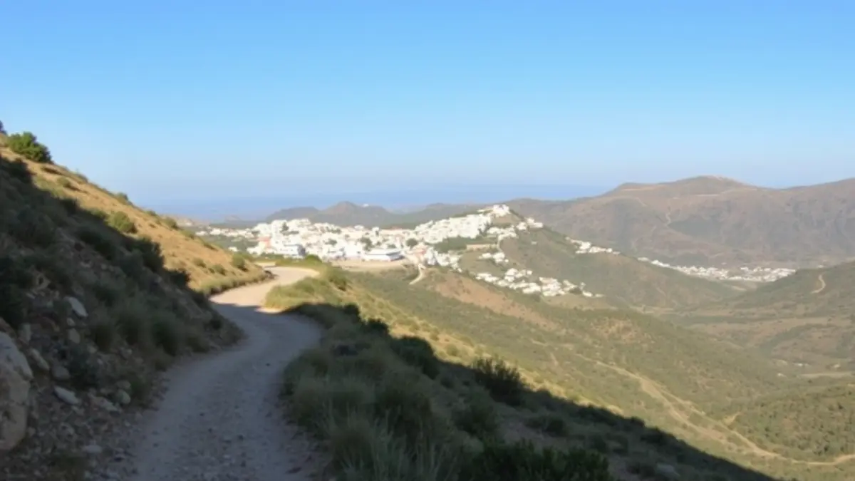 Imagen de un sendero de montaña en la Axarquía, con pueblos blancos al fondo.