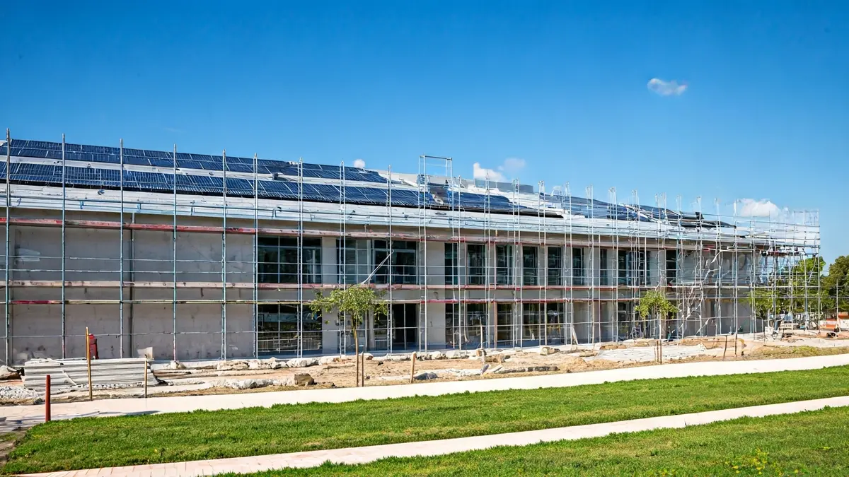 Image of a school under construction with solar panels and green areas.