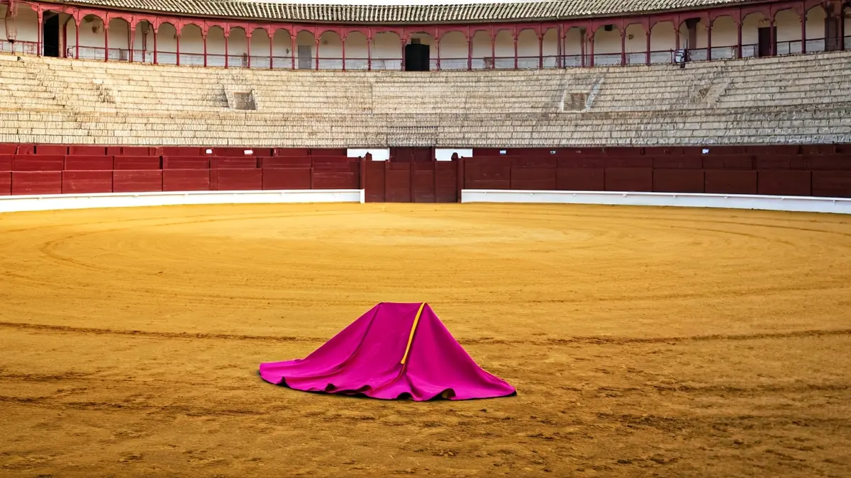 Image of the Maestranza Bullring in Seville with a bullfighting cape on the sand.