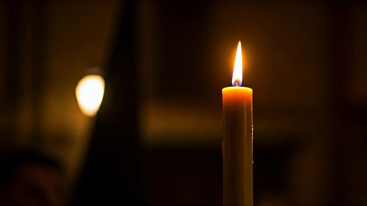 Generic image of a processional candle, with a warm light and a dark background.