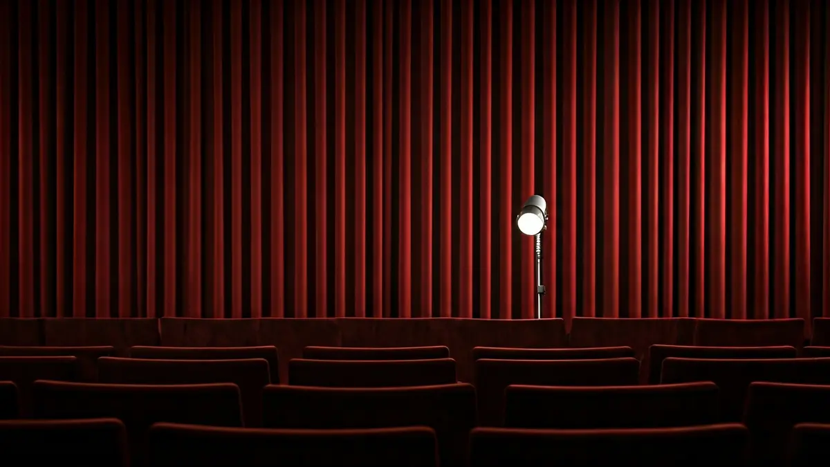 Imagen genérica de un escenario teatral con un micrófono y cortinas rojas.