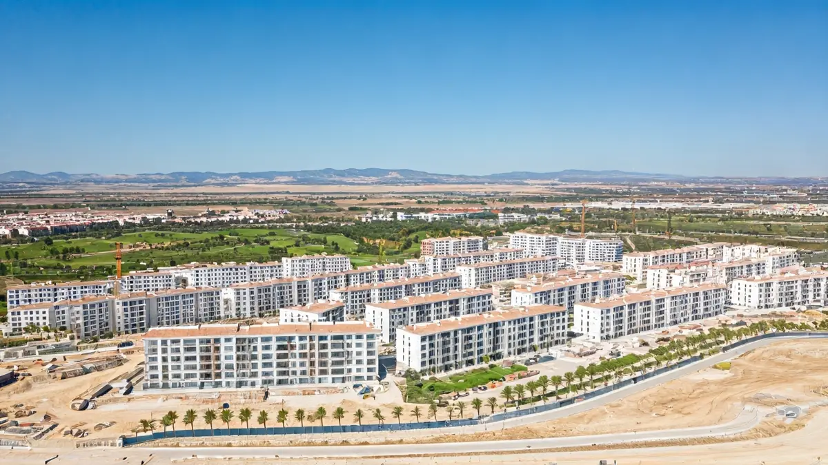 Aerial view of a residential development under construction with housing, green areas, and a golf course.