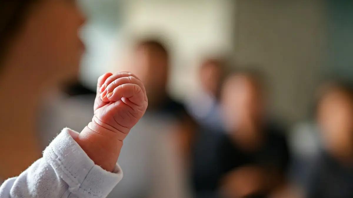 Imagen de un bebé recién nacido agarrando el dedo de un adulto en un entorno hospitalario.
