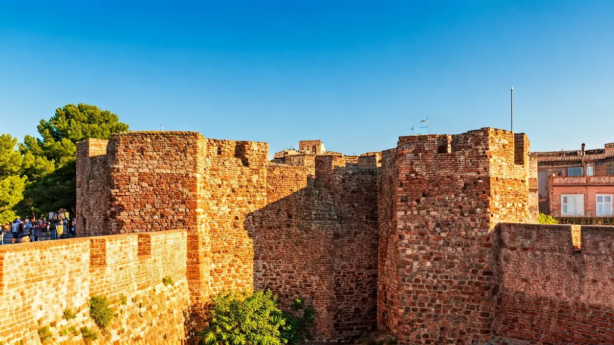 Imagen de las murallas rojizas de Niebla, Huelva, bajo el sol.