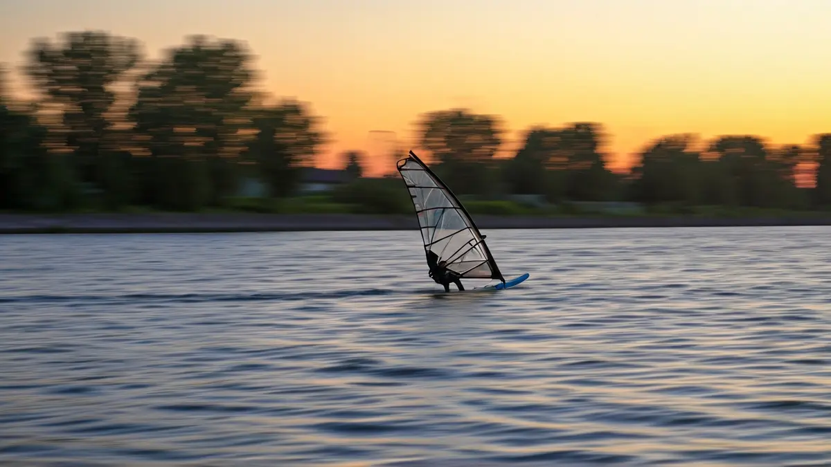 Imagen de un windsurfista en apuros en el río Guadalquivir al atardecer.