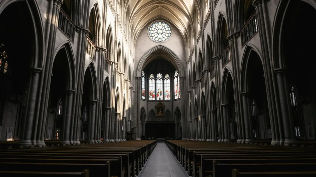 Interior de una catedral con techos altos y vidrieras, luz suave.