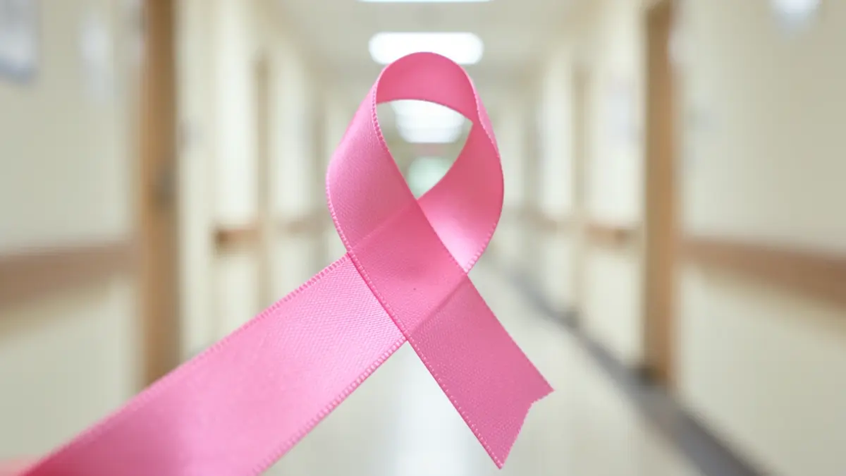 Cinta rosa símbolo de la lucha contra el cáncer de mama, con un fondo hospitalario desenfocado.