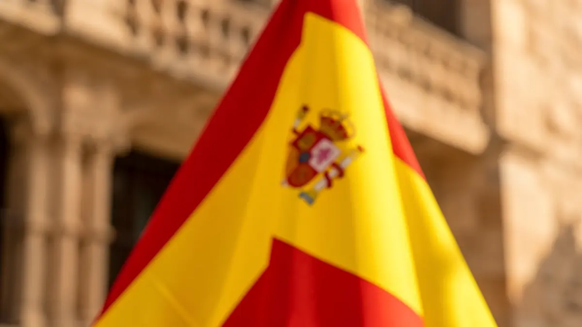 Banderas de España y Andalucía con arquitectura andaluza de fondo.