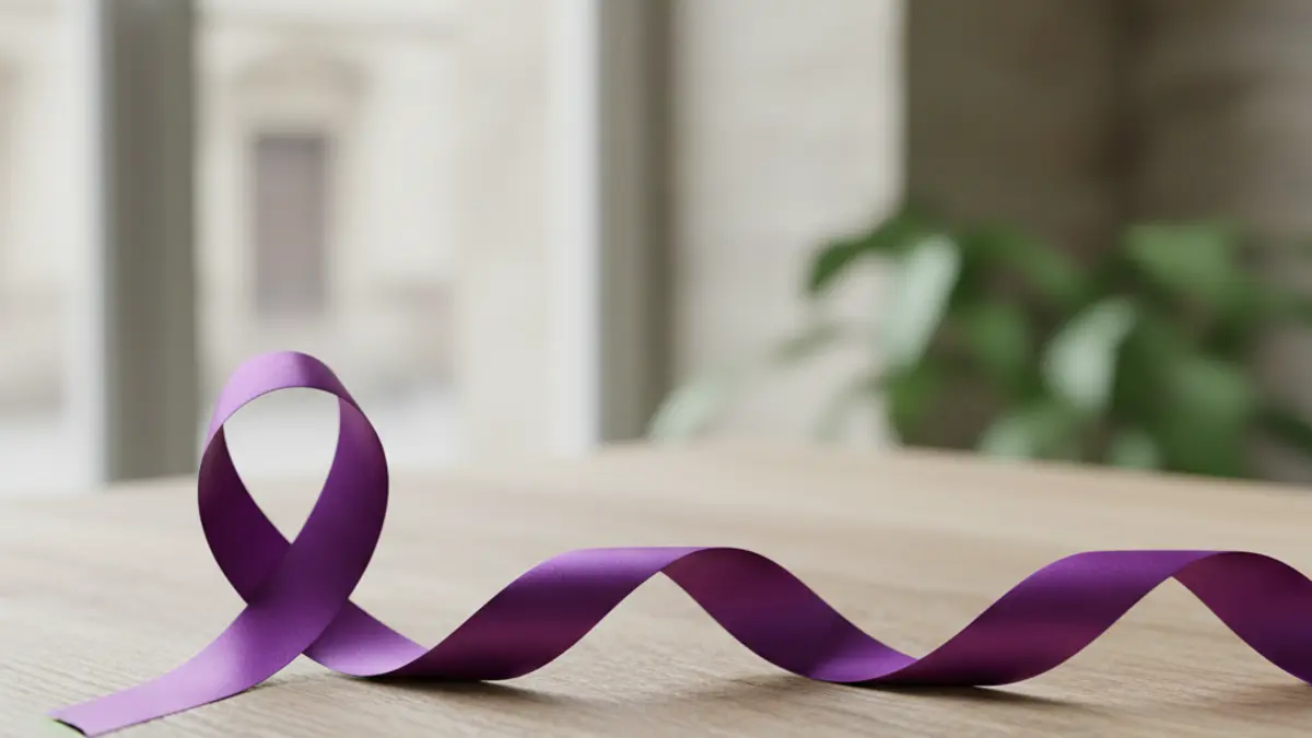 Generic image of a purple ribbon, symbol of fibromyalgia, on a wooden surface.