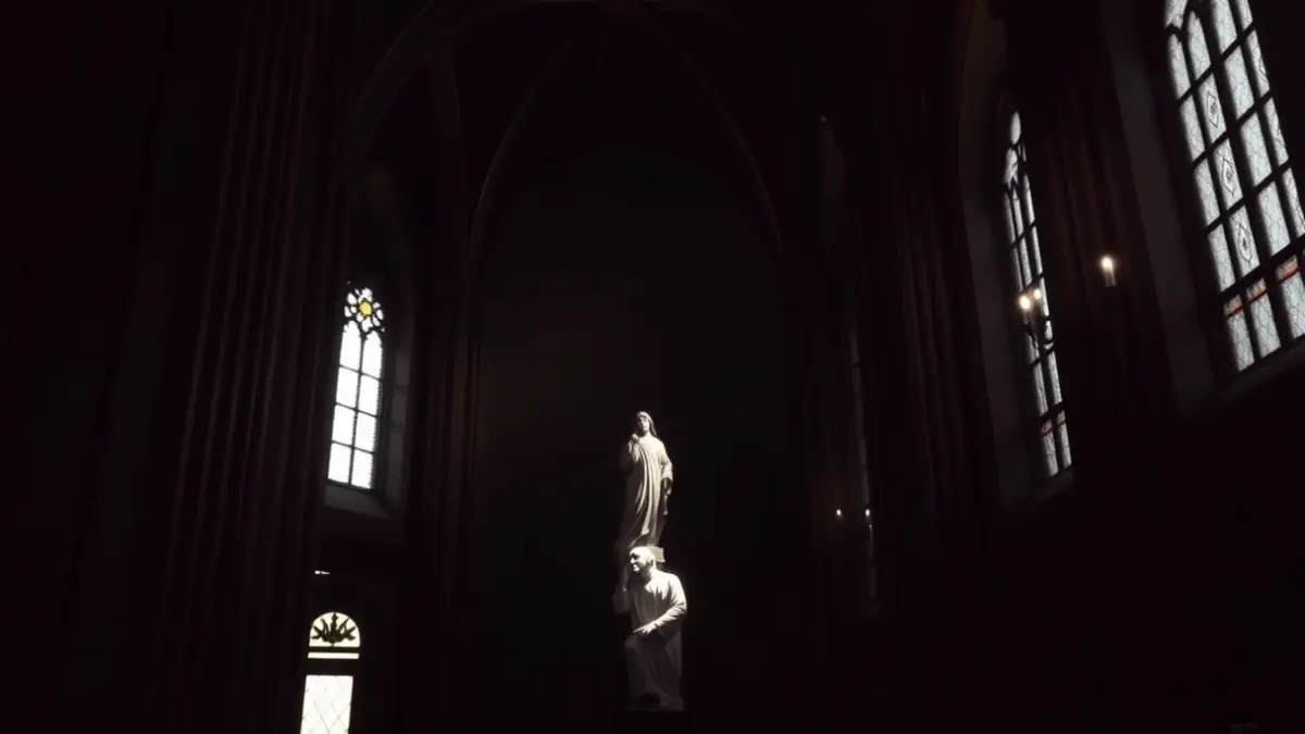 Imagen de una escultura religiosa iluminada en el interior de una catedral, creando una atmósfera de recogimiento.