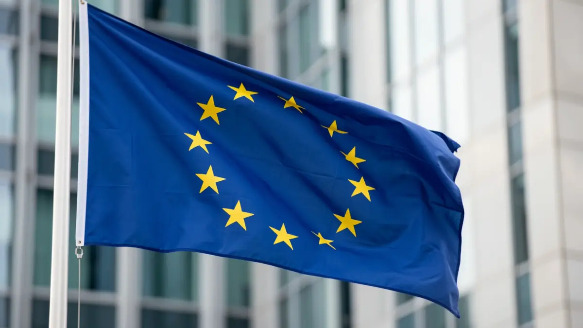 Bandera de la Unión Europea ondeando frente a un edificio moderno.