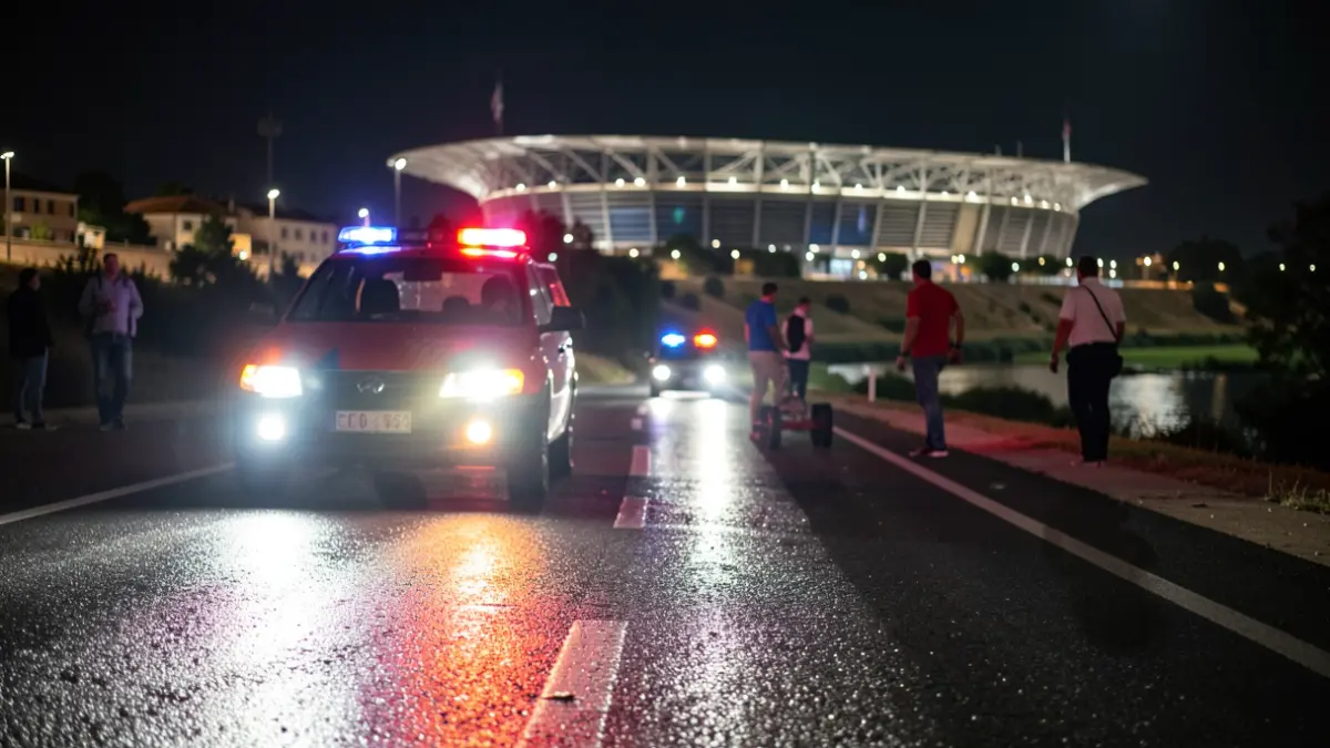 Generic image of emergency lights reflecting on wet asphalt near a river during a sporting event.