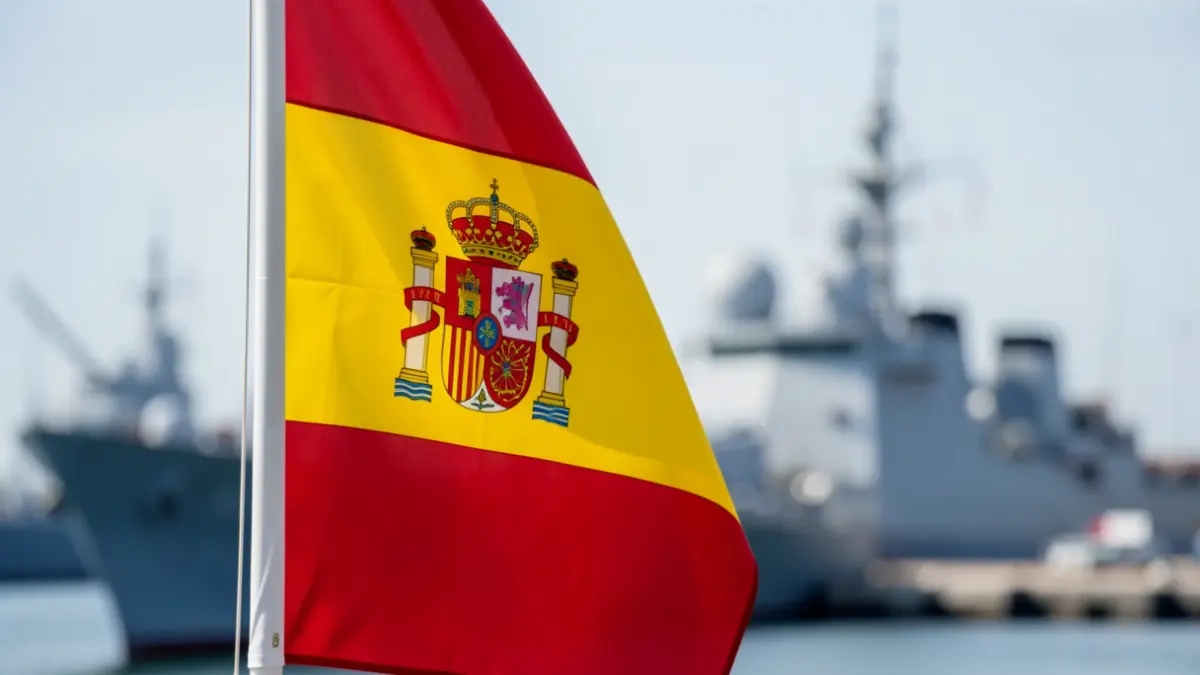 Spanish flag waving with the Rota naval base blurred in the background.