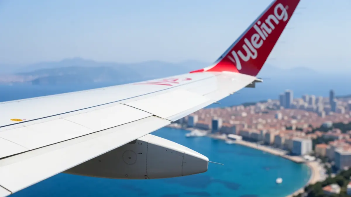 Imagen de un avión de Vueling despegando con la costa de Málaga de fondo.