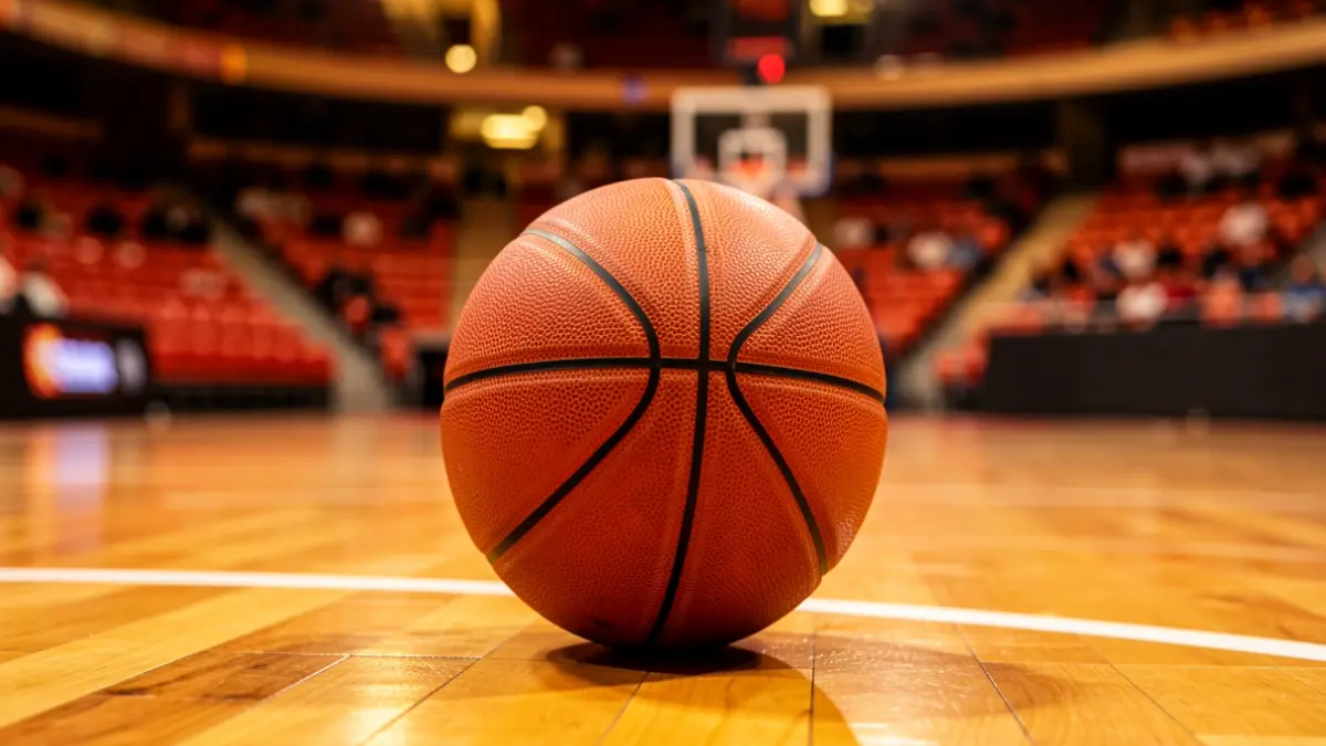 Imagen genérica de un balón de baloncesto sobre una pista de madera en un pabellón deportivo.