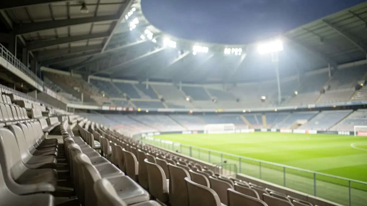 Empty football stadium grandstand illuminated by floodlights.