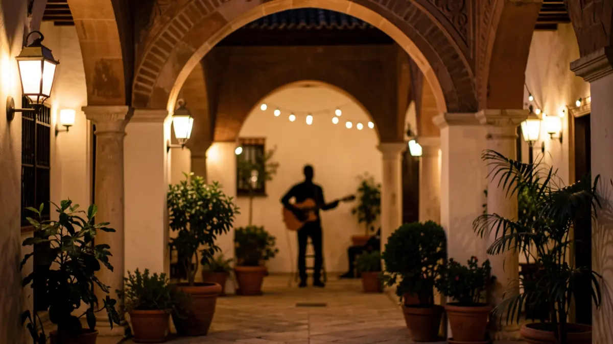 Pati andalús il·luminat de nit amb guitarrista al fons.