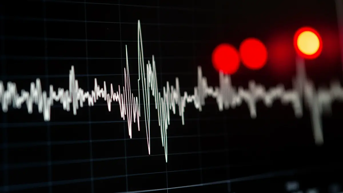 Vibrating seismograph needle with blurred emergency lights.