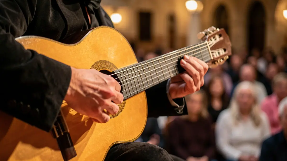 Hands of a flamenco guitarist playing a classical guitar on a historic Andalusian stage.