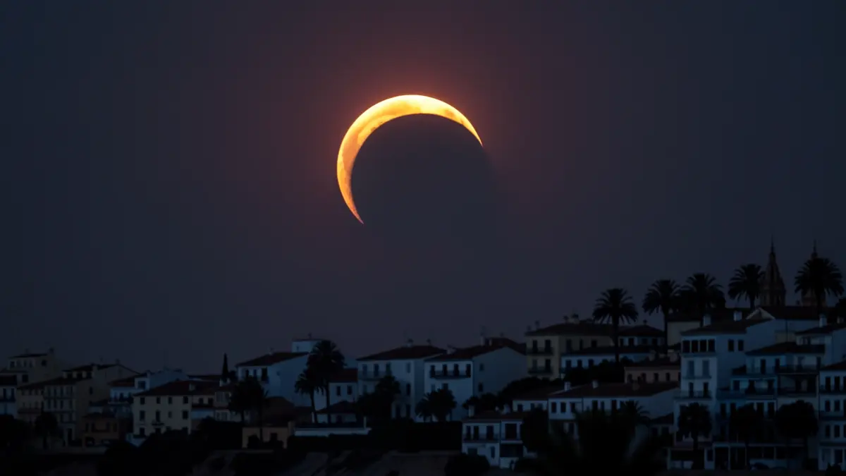 Vista del eclipse solar total sobre la costa de Almería, con el cielo oscureciéndose y siluetas de edificios.