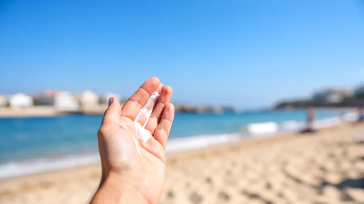 Persona aplicant crema solar a la platja d'Almuñécar per protegir-se del sol.
